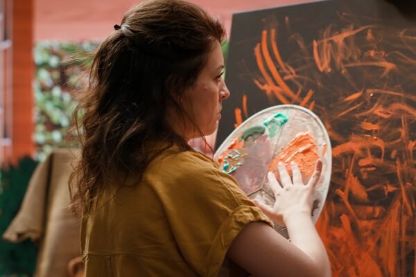 Painter works with finger painting technique on her latest artwork piece, contemporary art studio buzzes with creativity. Artist uses vibrant colors and for a modern paintwork design. Camera A.